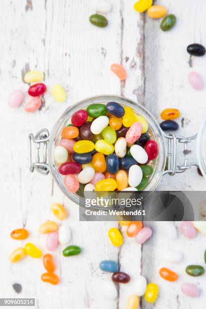 glass of colourful sweet jellybeans on white wood - jellybean stock pictures, royalty-free photos & images