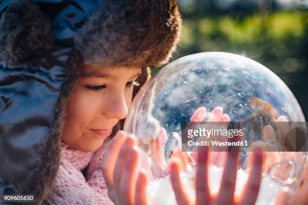 brother and sister looking into crystal ball filled with snow, making a wish - snow globe stock-fotos und bilder
