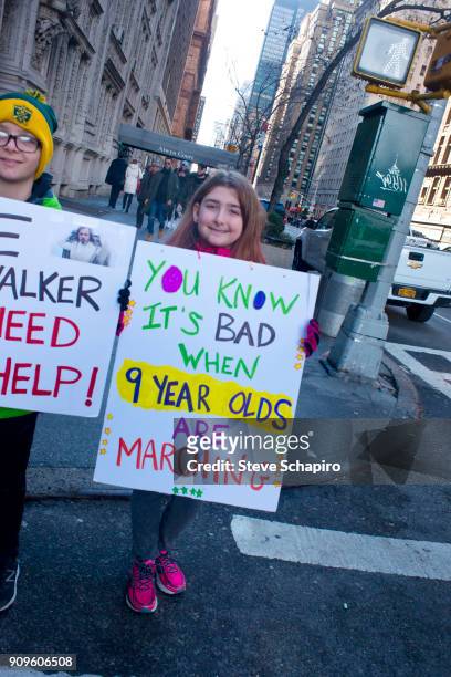 View of unidentified, young demonstrators, both with signs, at the Women's March on New York, New York, January 20, 2018. At left, the sign reads...