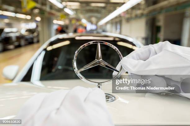 An employee mounts a Daimler AG Mercedes-Benz emblem to the hood of a S-Class sedans at the Mercedes-Benz plant on January 24, 2018 in Sindelfingen,...
