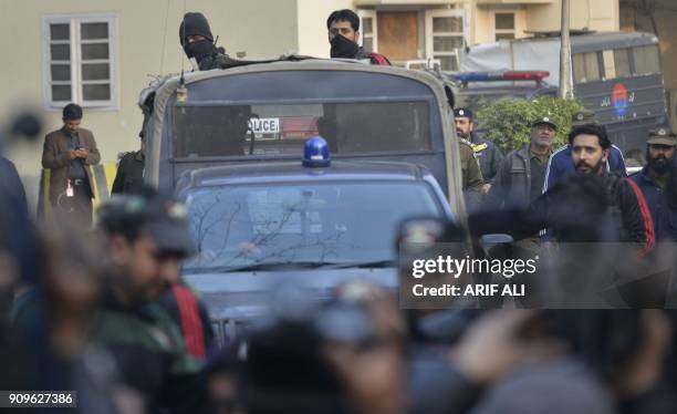 Pakistani policemen escort the police van carrying a suspect accused of raping and murdering a young girl as they leave an anti-terrorist court in...