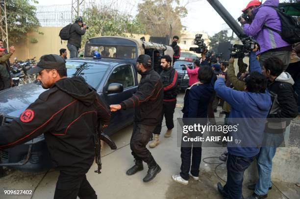 Pakistani policemen escort the police van carrying a suspect accused of raping and murdering a young girl as they leave an anti-terrorist court in...