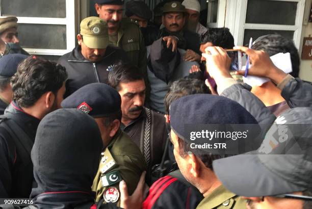 Pakistani policemen escort the suspect accused of raping and murdering a young girl as they leave an anti-terrorist court in Lahore on January 24,...