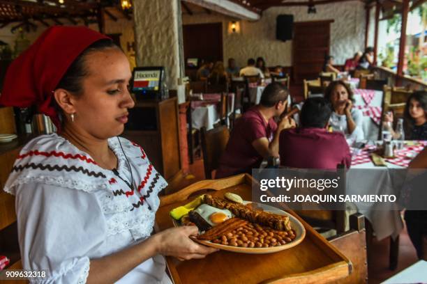 Waitress carries a "Bandeja Paisa" at a restaurant in Medellin, Antioquia department, on January 22, 2018. - The "Bandeja Paisa" is a traditional...