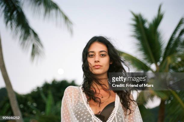 tan young woman on tropical beach looks confidently at the camera - franse overzeese gebieden stockfoto's en -beelden