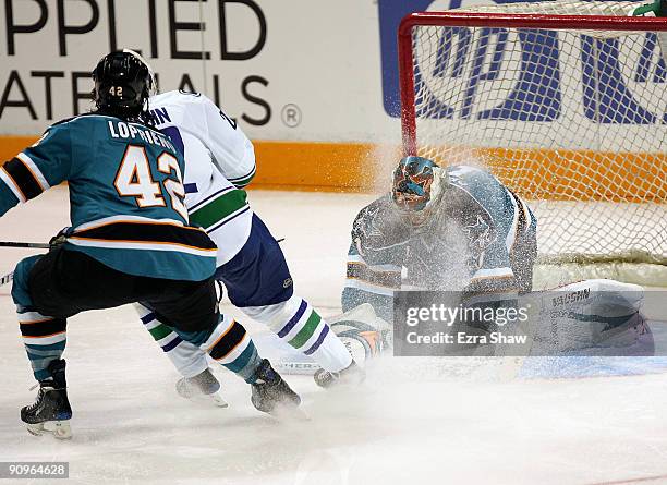 Goalie Thomas Greiss of the San Jose Sharks makes a save on a shot taken by Daniel Sedin of the Vancouver Canucks as Joe Loprieno plays defense for...