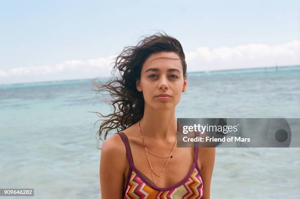 portrait of a tan young woman staring confidently into the camera brown hair blowing in wind - territorios franceses de ultramar fotografías e imágenes de stock