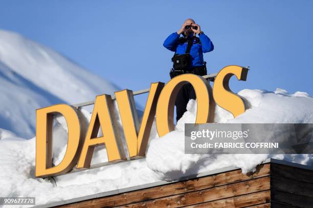 Swiss armed security personnel stand guard on the rooftop of a hotel, next to letters covered in snow reading "Davos", near the Congress Centre on...