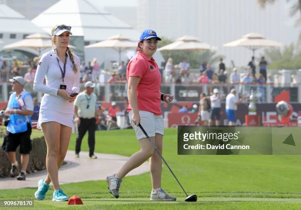 Saoirse Lambe of Ireland who won a global competition to play with Rory McIlroy and Niall Horan is assited by Paige Spiranac of the United States...