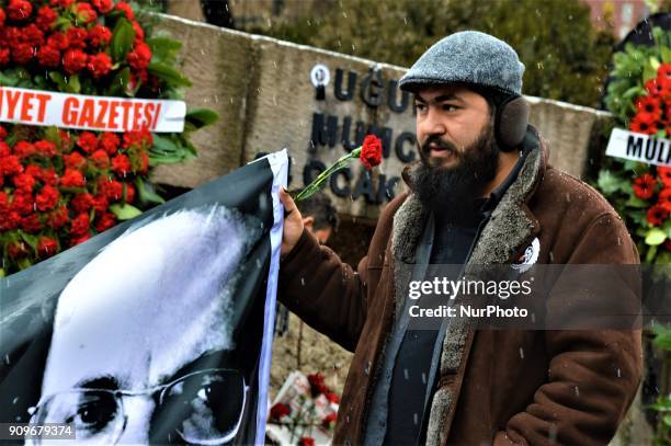 Man holds a banner as people gather on the spot, where Turkish journalist Ugur Mumcu was assassinated, during a commemoration to mark the 25th...