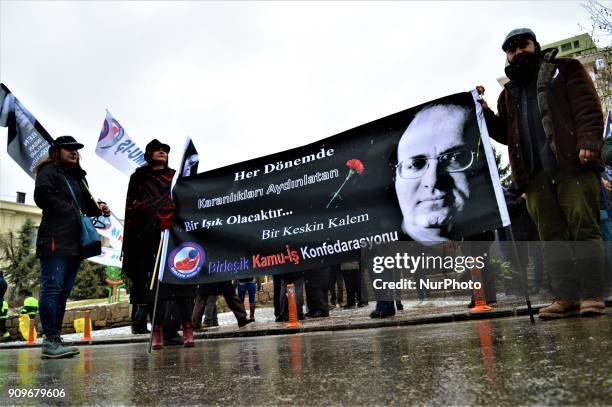 People hold a banner as they gather on the spot, where Turkish journalist Ugur Mumcu was assassinated, during a commemoration to mark the 25th...