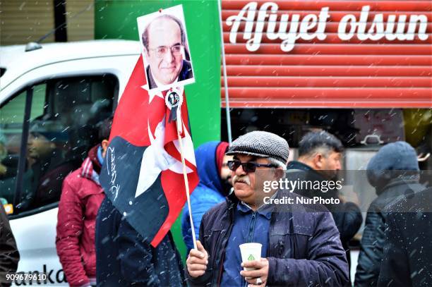 Man holds a Turkish flag and a portrait as people gather on the spot, where Turkish journalist Ugur Mumcu was assassinated, during a commemoration to...