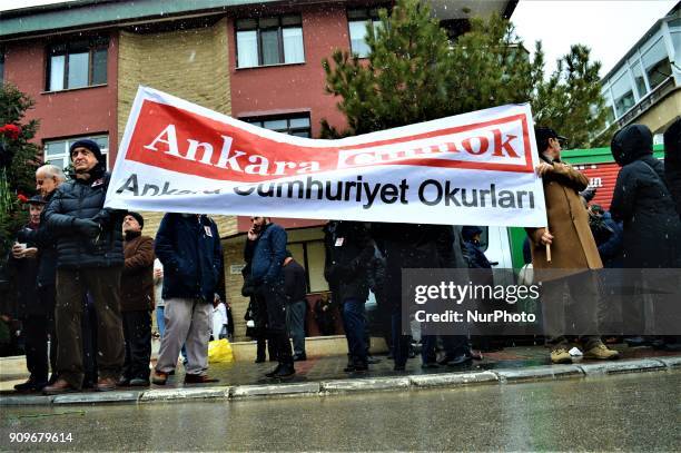 People hold a banner as they gather on the spot, where Turkish journalist Ugur Mumcu was assassinated, during a commemoration to mark the 25th...