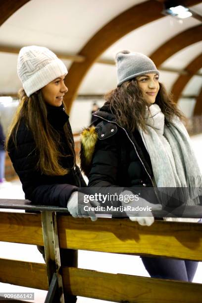 due belle ragazze che indossano caldi vestiti invernali pattinaggio su ghiaccio - capelli ghiaccio foto e immagini stock