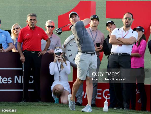 Rory McIlroy of Northern Ireland plays a shot during the pro-am watched closely by Paige Spiranac of The United States as a preview for the Omega...