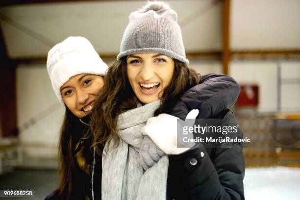 due belle ragazze che indossano caldi vestiti invernali pattinaggio su ghiaccio - capelli ghiaccio foto e immagini stock