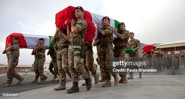 Italian ISAF soldiers carry coffins torwards a plane during a memorial service for the six soldiers killed after a suicide car bomb hit a military...