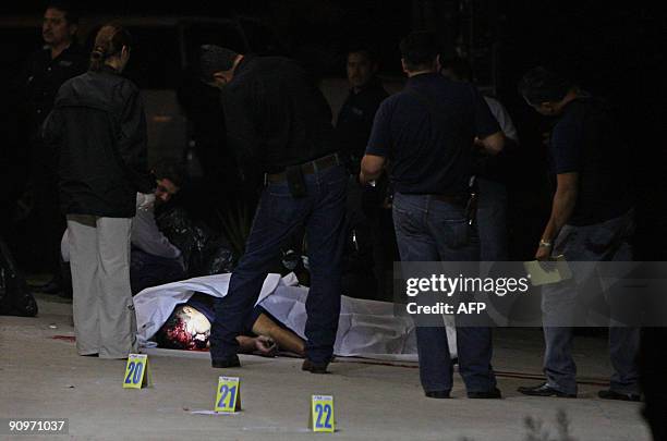 Police surround the corpse of a murdered colleague in Tijuana, Mexico the night of September 18, 2009. Three police officers were killed and one more...