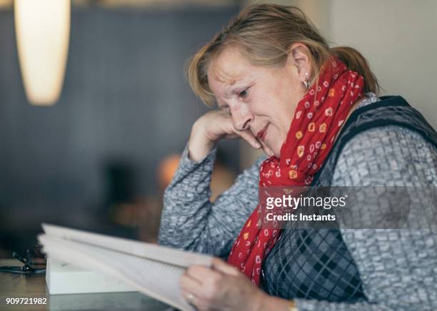 aktive sechzig jahre alten frau in einem café ein lehrbuch zu lesen. - 63 year old female stock-fotos und bilder
