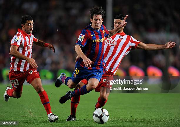 Lionel Messi of Barcelona is fouled by Tomas Ujfalusi and Simao of Atletico Madrid during the La Liga match between Barcelona and Atletico Madrid at...