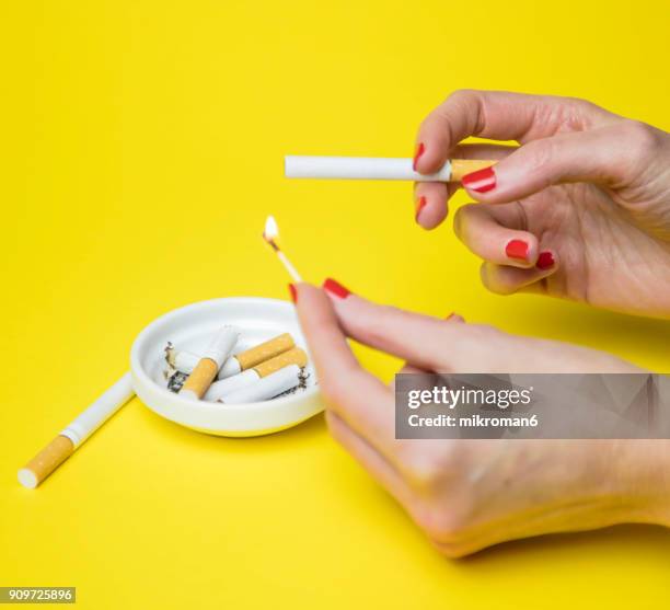 woman lighting a cigarette - zigarettenfilter stock-fotos und bilder