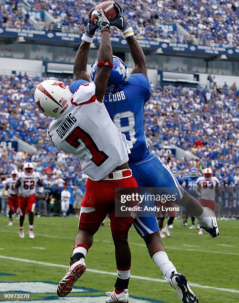 Randall Cobb of the Kentucky Wildcats reaches for the game winning touchdown while defended by Karldell Dunning of the Louisville Cardinals during...