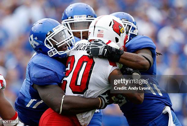 Victor Anderson of the Louisville Cardinals is tackled by three Kentucky Wildcats during the game at Commonwealth Stadium on September 19, 2009 in...