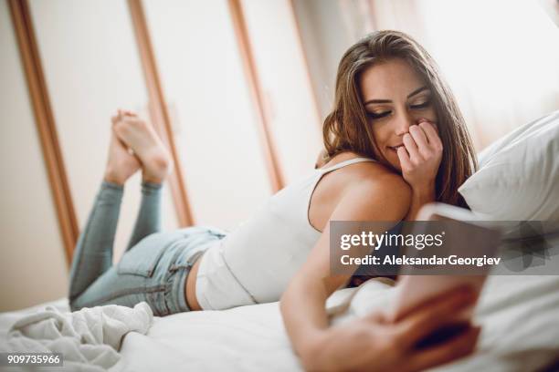 joven sonriente mujer de mentira en su dormitorio y hacer selfie - mujer seductora fotografías e imágenes de stock