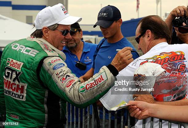 John Force, driver of the Castrol GTX High Mileage Ford signs a fan's shirt during qualifying for the NHRA Carolinas Nationals on September 19, 2009...