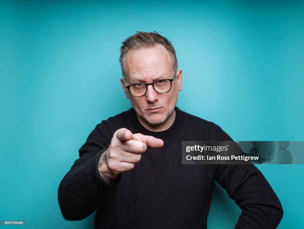 Portrait of middle-aged man on blue background pointing