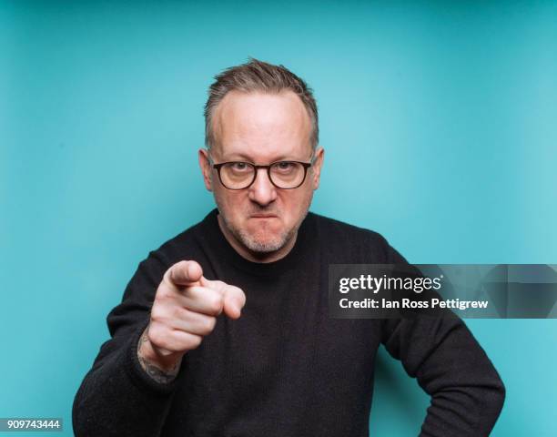 portrait of middle-aged man on blue background pointing - middle finger stock-fotos und bilder