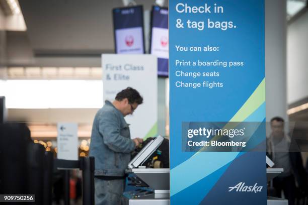 Sign displaying Alaska Air Group Inc. Self check-in information is seen at the San Francisco International Airport in San Francisco, California,...