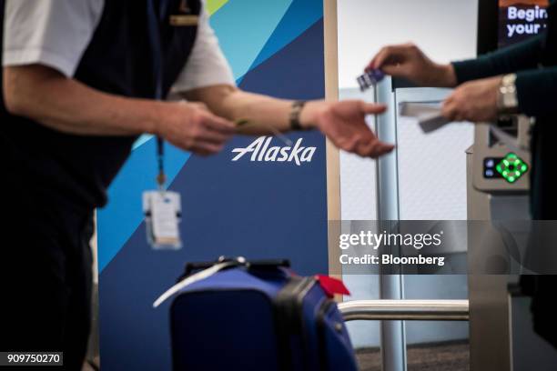 An employee hands a traveler a boarding pass at an Alaska Air Group Inc. Check-in counter at the San Francisco International Airport in San...