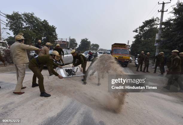Policemen clearing out the pile of gravel dumped on road in order to block the traffic near village Bhondsi in Gurgaon allegedly by activists of...