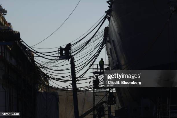 The silhouettes of shipyard workers are seen on The USS Truxtun destroyer in the dry dock at the General Dynamics Corp. NASSCO shipyard facility on...
