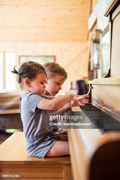 niedlichen kinder versuchen, zu hause klavier spielen. - kids instruments stock-fotos und bilder