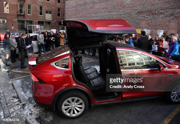 Colorado Governor John Hickenlooper, left, holds a press conference alongside a Tesla Model X electric car at The Alliance Center promoting his...
