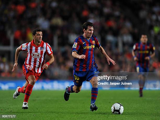 Lionel Messi of Barcelona runs with the ball flanked by Simao of Atletico Madrid during the La Liga match between Barcelona and Atletico Madrid at...