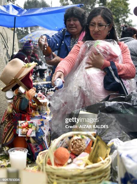 Women give an Ekeko -Aymara god of abundance- statuette something to drink and to smoke during the inauguuration of the Alasitas Fair in La Paz on...