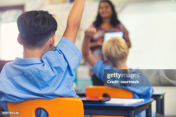 aboriginal elementary school  teacher giving a presentation to the class. the students have their hands raised to ask  questions in the classroom - teachers education uniform stock pictures, royalty-free photos & images