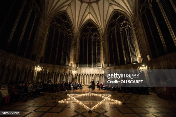 Members of the congregation are seated around 600 candles, depicting the Star of David, set out during an event to commemorate Holocaust Memorial Day...