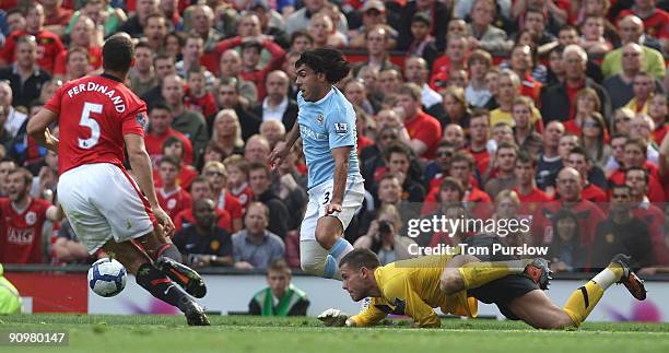 Carlos Tevez of Manchester City rounds Ben Foster of Manchester United in the build-up to Gareth Barry scoring their first goal during the Barclays...