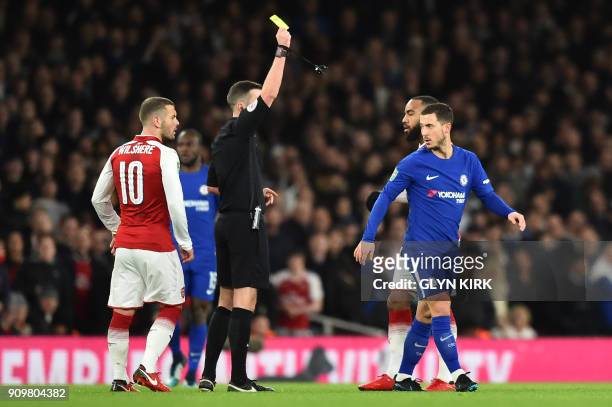 Chelsea's Belgian midfielder Eden Hazard is booked by referee Michael Oliver for a tackle on Arsenal's German midfielder Mesut Ozil during the League...