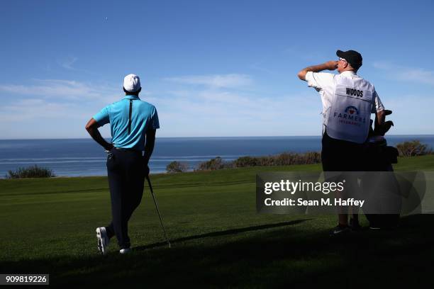 Tiger Woods and caddy Joe LaCava wait along the 16th fairway during the pro-am round of the Farmers Insurance Open at Torrey Pines Golf Course on...