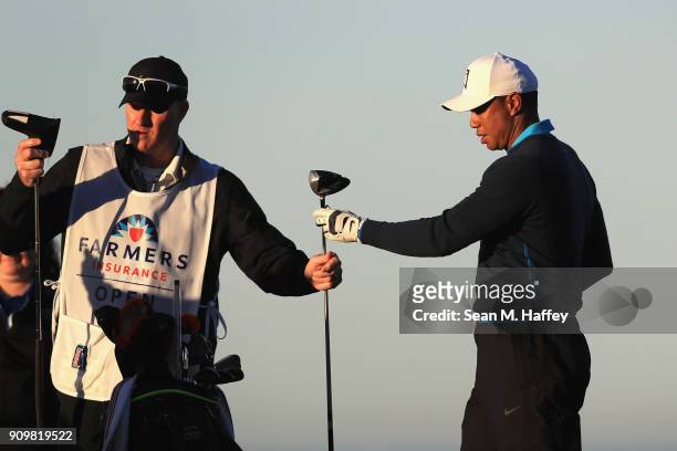 Caddy Joe LaCava hands Tiger Woods a club on the fourth tee during the pro-am round of the Farmers Insurance Open at Torrey Pines Golf Course on...