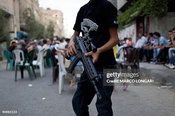 Palestinian boy plays with a new plastic gun at the funeral of PFLP militant Mahmud Nassir, who was killed alongside an unidentified Hamas militant...