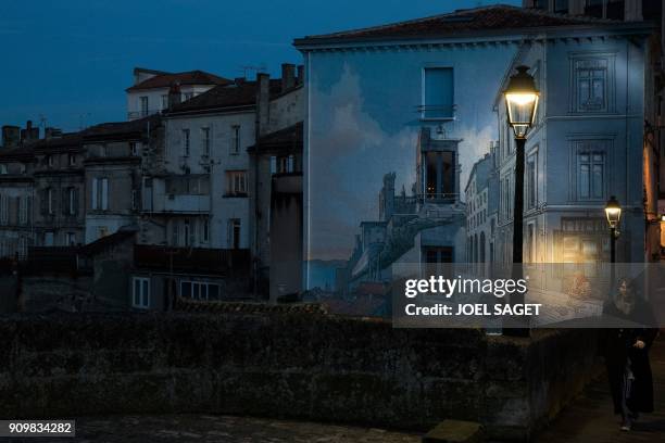 Woman passes near a wall with the painting 'La fille des remparts' after a drawing by Max Cabannes in Angouleme on January 24 on the opening day of...