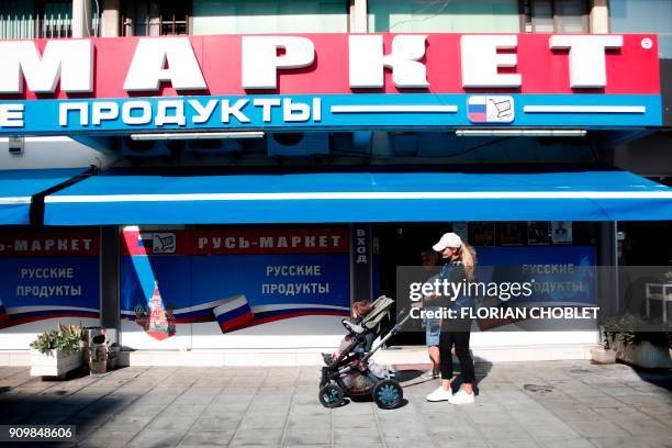 Russian woman walks past a Russian supermarket in the Cypriot port city of Limassol on January 10, 2018. / AFP PHOTO / Florian CHOBLET