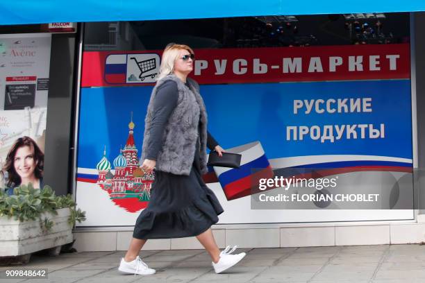 Belarusian woman walks past a Russian supermarket in the Cypriot port city of Limassol on January 10, 2018. / AFP PHOTO / Florian CHOBLET