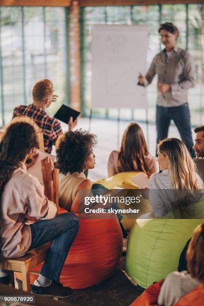 young creative coworkers talking during a business presentation at casual office. - training bean bag stock pictures, royalty-free photos & images